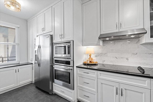 kitchen featuring white cabinets, decorative backsplash, dark tile patterned floors, and stainless steel appliances