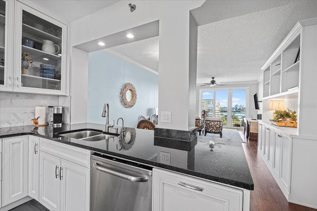 kitchen featuring kitchen peninsula, stainless steel dishwasher, dark stone counters, sink, and white cabinetry