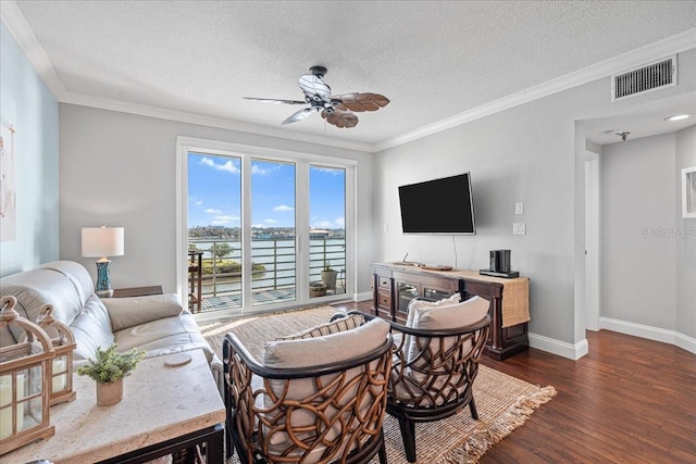 living room with a textured ceiling, dark hardwood / wood-style floors, ceiling fan, and ornamental molding