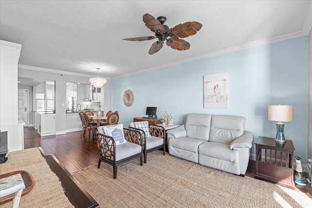 living room featuring a textured ceiling, ceiling fan with notable chandelier, dark wood-type flooring, crown molding, and sink