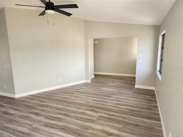 unfurnished room featuring hardwood / wood-style floors, ceiling fan, and vaulted ceiling