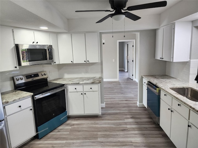 kitchen featuring sink, ceiling fan, light wood-type flooring, appliances with stainless steel finishes, and white cabinetry