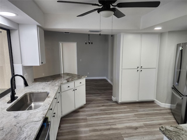 kitchen with white cabinets, appliances with stainless steel finishes, light stone counters, and sink