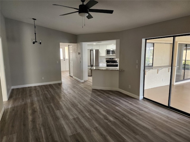 unfurnished living room featuring hardwood / wood-style floors and ceiling fan with notable chandelier