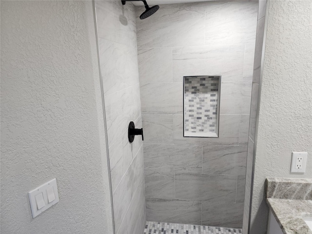 bathroom with vanity and tiled shower