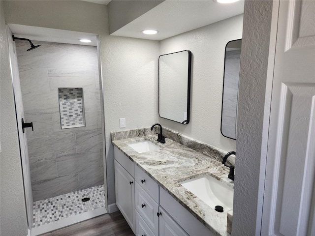 bathroom with hardwood / wood-style floors, vanity, and tiled shower