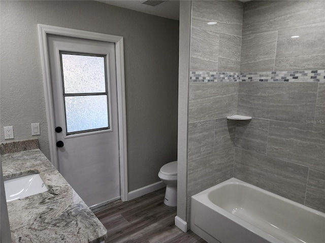 full bathroom with vanity, hardwood / wood-style flooring, toilet, and tiled shower / bath combo