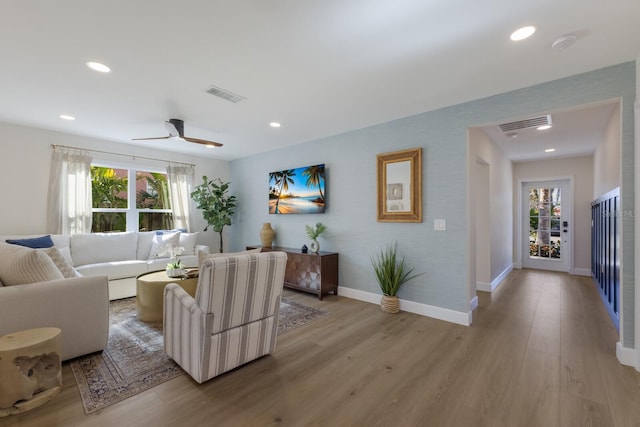 living room featuring ceiling fan, plenty of natural light, and light hardwood / wood-style floors