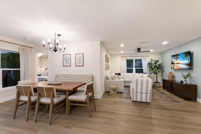 dining space with light hardwood / wood-style floors and ceiling fan with notable chandelier