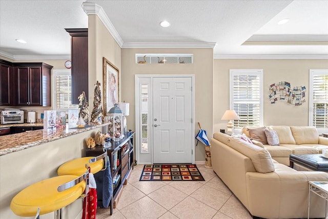 tiled foyer featuring a textured ceiling and crown molding