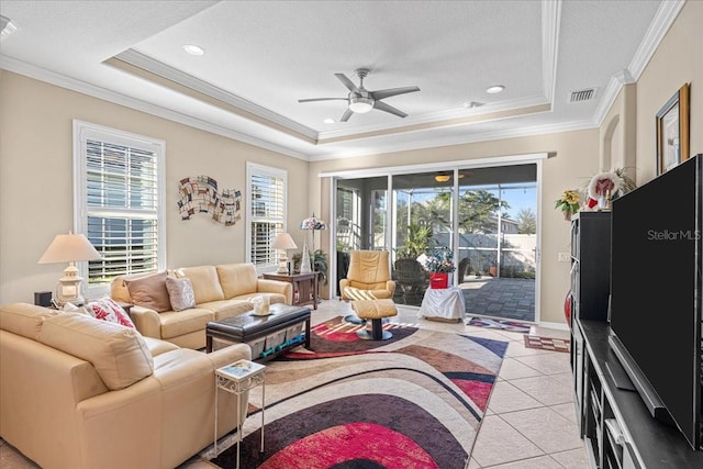 living room with crown molding, ceiling fan, light tile patterned floors, a textured ceiling, and a tray ceiling