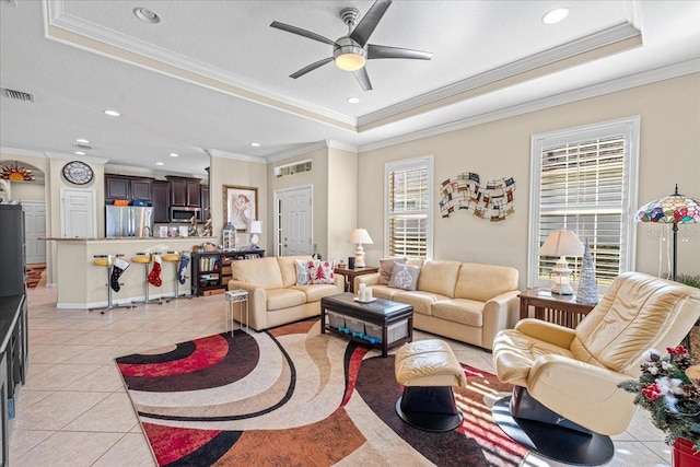 living room featuring a raised ceiling, crown molding, and light tile patterned floors