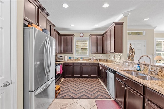 kitchen with light stone countertops, appliances with stainless steel finishes, crown molding, sink, and light tile patterned flooring