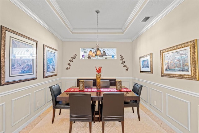 dining area featuring a chandelier, a raised ceiling, and crown molding