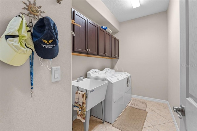 clothes washing area featuring cabinets, light tile patterned floors, a textured ceiling, and separate washer and dryer