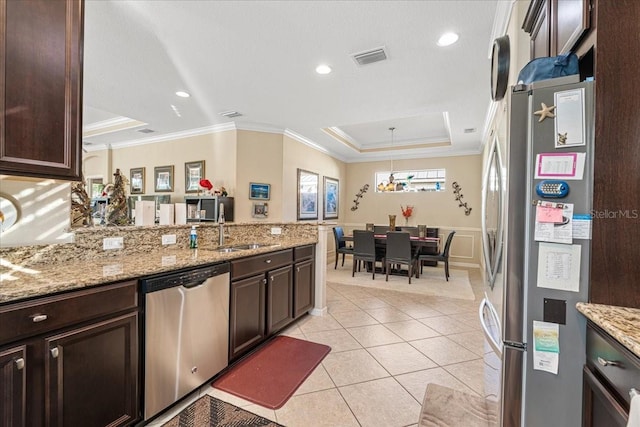 kitchen with sink, pendant lighting, a tray ceiling, light tile patterned floors, and appliances with stainless steel finishes