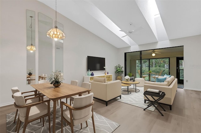 dining room featuring hardwood / wood-style flooring, ceiling fan with notable chandelier, and lofted ceiling with skylight