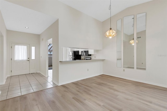 foyer entrance featuring lofted ceiling, light hardwood / wood-style floors, and a notable chandelier