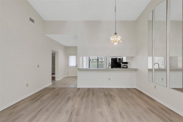 unfurnished living room featuring light wood-type flooring and an inviting chandelier