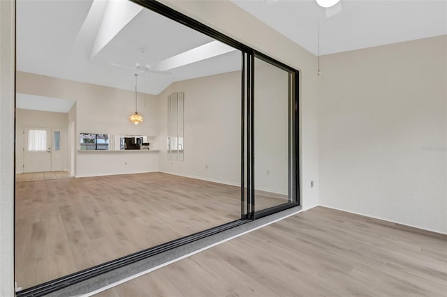 unfurnished living room with ceiling fan, lofted ceiling, and light hardwood / wood-style flooring