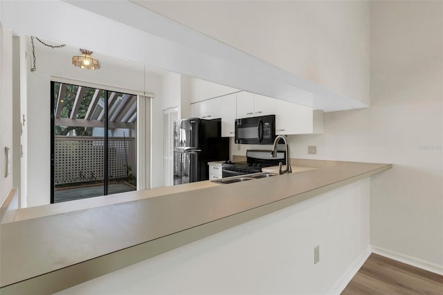 kitchen featuring sink, white cabinets, black appliances, and wood-type flooring