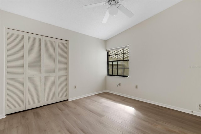 unfurnished bedroom with ceiling fan, lofted ceiling, light hardwood / wood-style flooring, and a closet