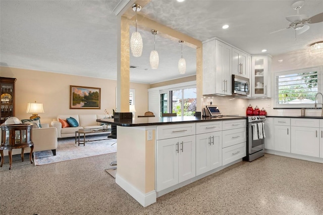 kitchen with stainless steel appliances, kitchen peninsula, hanging light fixtures, and white cabinets