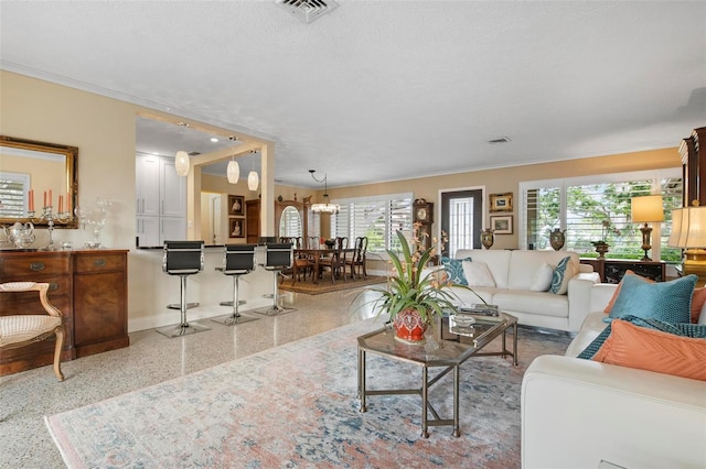 living area featuring visible vents, crown molding, a textured ceiling, and baseboards