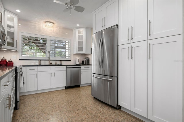 kitchen featuring stainless steel appliances, dark countertops, glass insert cabinets, white cabinetry, and a sink