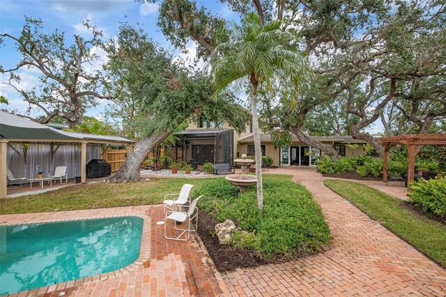 view of pool with a patio, grilling area, a gazebo, fence, and a pergola