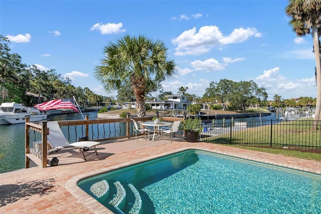 view of swimming pool with a deck with water view, fence, and a fenced in pool