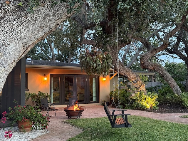 view of front of home with an outdoor fire pit, a patio area, and stucco siding