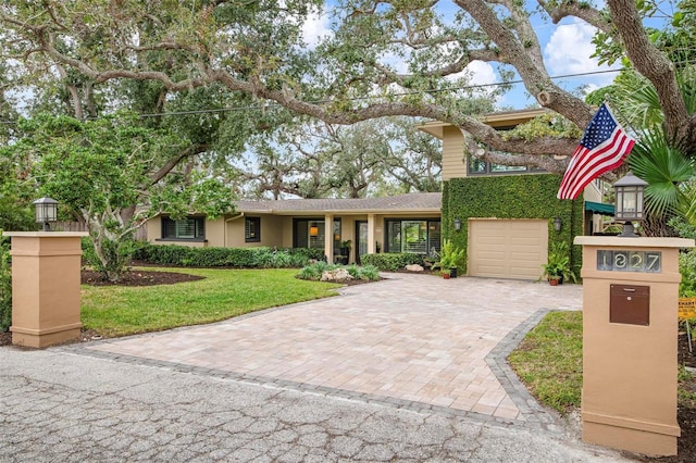 view of front of house featuring decorative driveway, a front yard, and stucco siding