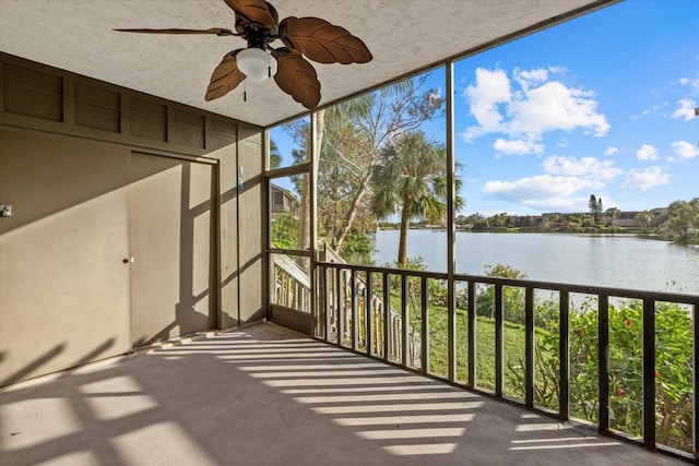 unfurnished sunroom with ceiling fan, a water view, and a wealth of natural light