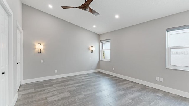 empty room with ceiling fan, lofted ceiling, and light wood-type flooring