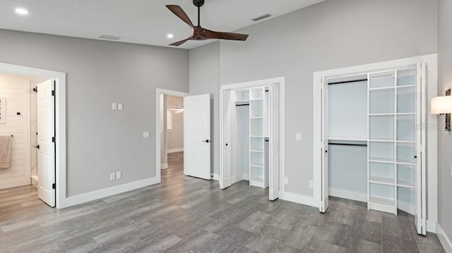 unfurnished bedroom with ensuite bathroom, hardwood / wood-style floors, ceiling fan, and high vaulted ceiling