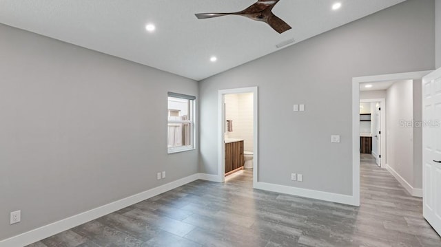 unfurnished bedroom with hardwood / wood-style floors, ceiling fan, connected bathroom, and vaulted ceiling