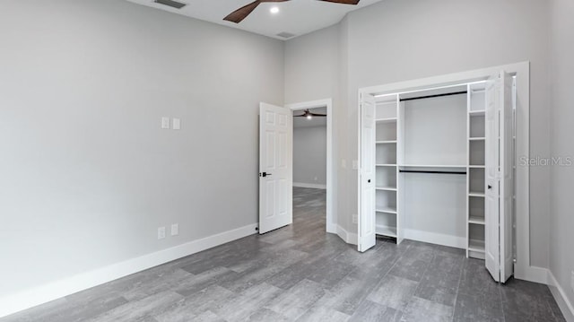 unfurnished bedroom featuring a towering ceiling, a closet, ceiling fan, and dark hardwood / wood-style floors