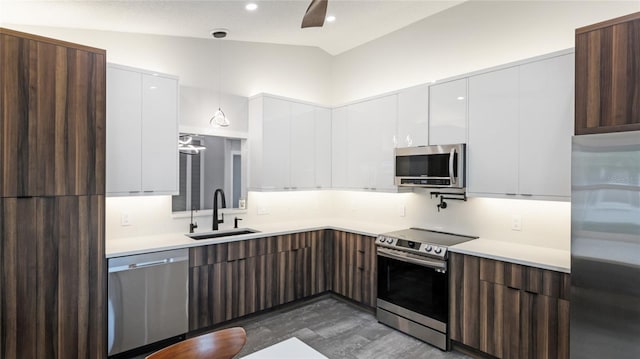 kitchen featuring stainless steel appliances, white cabinetry, lofted ceiling, and sink