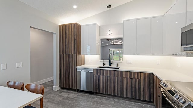 kitchen featuring white cabinetry, sink, decorative light fixtures, vaulted ceiling, and appliances with stainless steel finishes