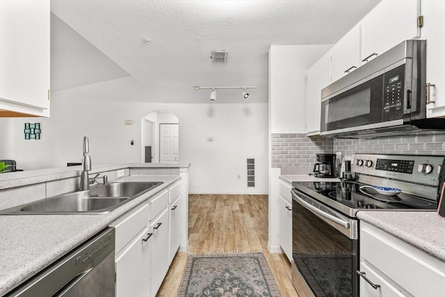 kitchen featuring sink, light hardwood / wood-style flooring, a textured ceiling, appliances with stainless steel finishes, and white cabinetry