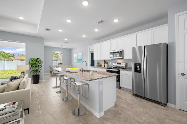 kitchen featuring stainless steel appliances, sink, a center island with sink, white cabinets, and a breakfast bar area