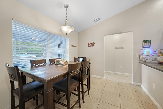 dining area with light tile patterned floors and vaulted ceiling