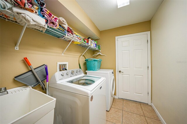 laundry room featuring washing machine and clothes dryer, light tile patterned floors, and sink