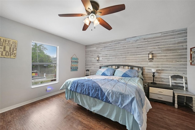 bedroom with ceiling fan, wood walls, and dark hardwood / wood-style floors