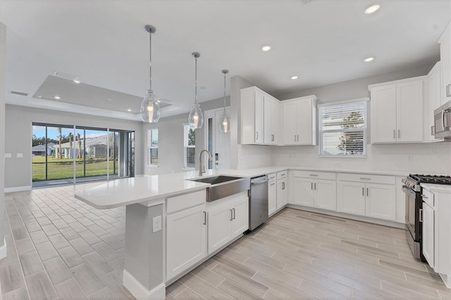 kitchen with kitchen peninsula, white cabinetry, sink, and stainless steel appliances