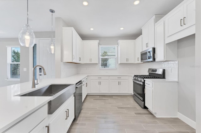 kitchen with white cabinets, decorative backsplash, stainless steel appliances, and hanging light fixtures