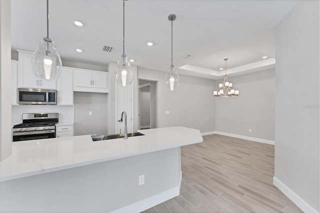 kitchen featuring appliances with stainless steel finishes, a raised ceiling, sink, pendant lighting, and white cabinets