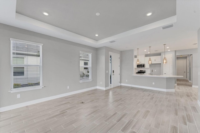 unfurnished living room with plenty of natural light and a tray ceiling