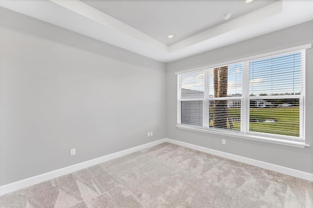 carpeted spare room with a tray ceiling